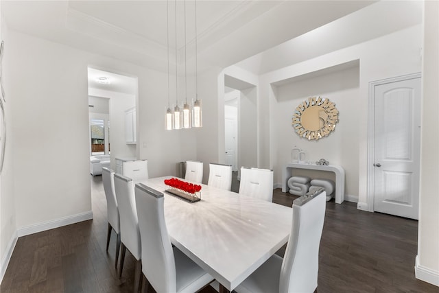 dining space with dark wood-style floors, a raised ceiling, and baseboards