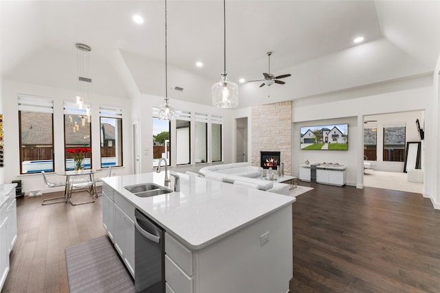 kitchen featuring ceiling fan, a kitchen island with sink, sink, pendant lighting, and a fireplace