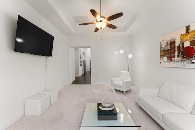 carpeted living room featuring ceiling fan and a tray ceiling