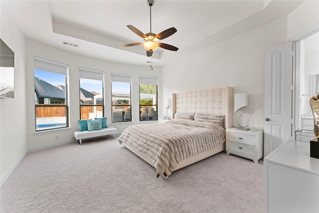 carpeted bedroom featuring a tray ceiling and ceiling fan