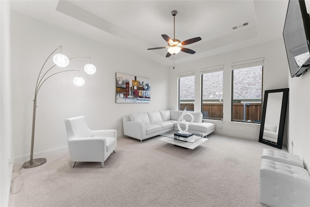 living area with carpet flooring, visible vents, baseboards, a ceiling fan, and a raised ceiling