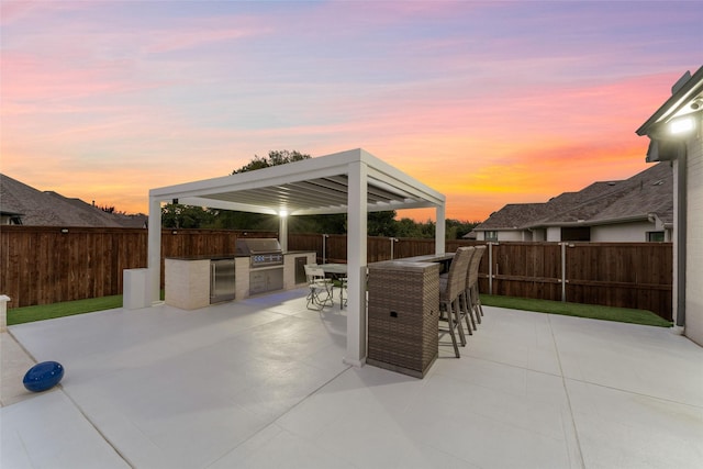 view of patio with a fenced backyard, a grill, an outdoor kitchen, and outdoor dry bar