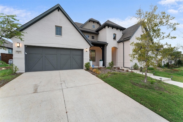 view of front of property featuring a garage, driveway, brick siding, and a front yard