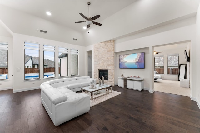 living area featuring visible vents, lofted ceiling, dark wood-style floors, ceiling fan, and a stone fireplace