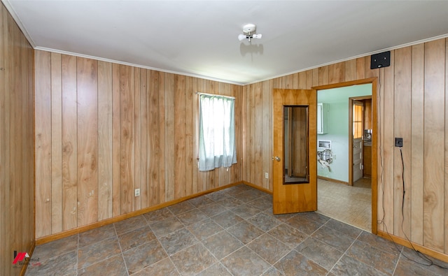 spare room with ornamental molding and wooden walls