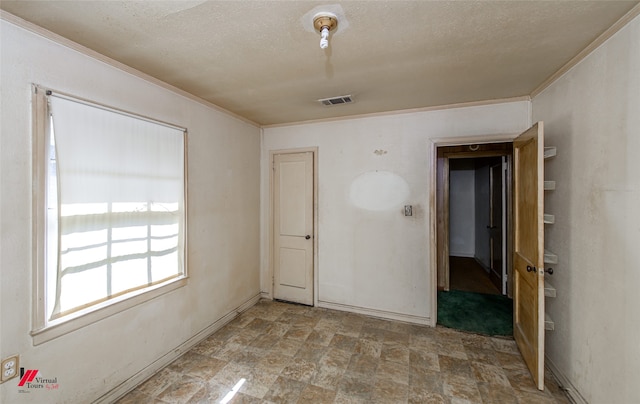 spare room with crown molding and a textured ceiling