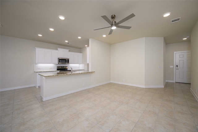 kitchen with appliances with stainless steel finishes, white cabinetry, light tile patterned floors, decorative backsplash, and light stone counters