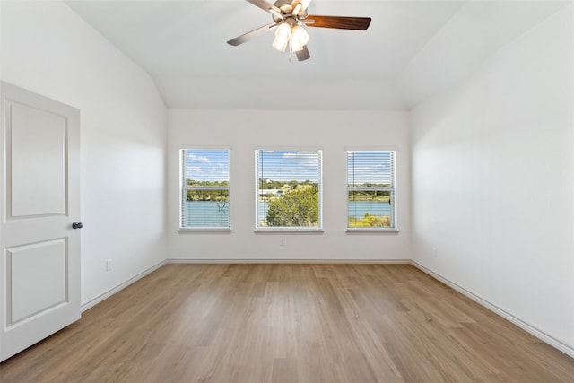 spare room featuring ceiling fan, light hardwood / wood-style flooring, vaulted ceiling, and a healthy amount of sunlight