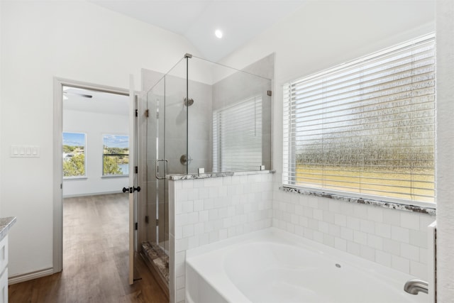 bathroom with plus walk in shower, vaulted ceiling, hardwood / wood-style flooring, and vanity