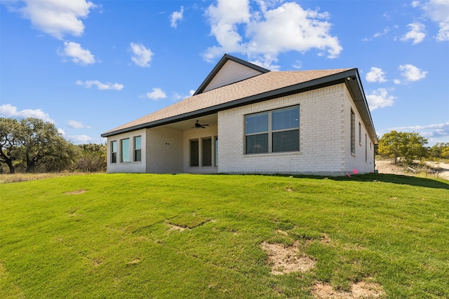 back of house with ceiling fan and a yard