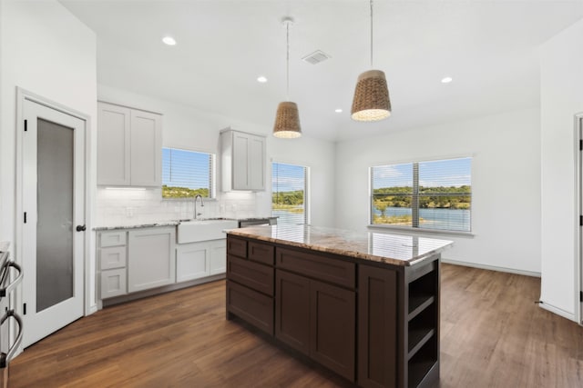 kitchen with white cabinets, light stone countertops, decorative light fixtures, dark hardwood / wood-style floors, and sink