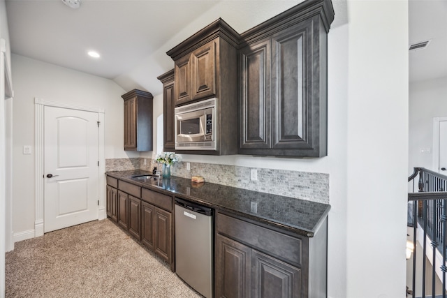 kitchen with dark brown cabinetry, appliances with stainless steel finishes, vaulted ceiling, and light colored carpet