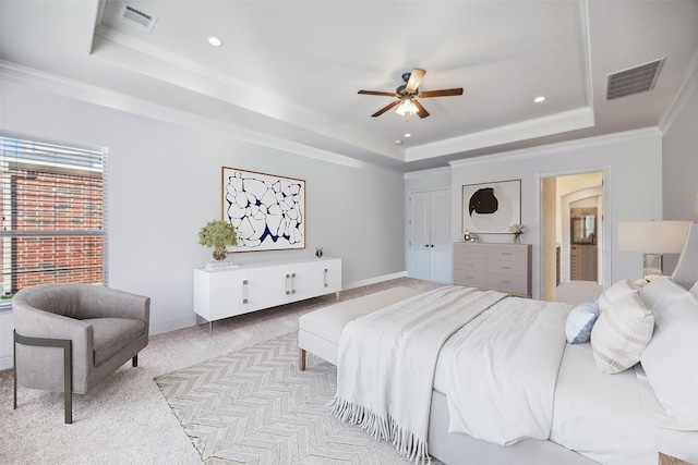 bedroom featuring ceiling fan, crown molding, a tray ceiling, and light carpet