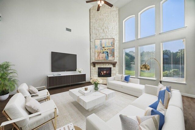 living room with a towering ceiling, hardwood / wood-style floors, a fireplace, and a healthy amount of sunlight