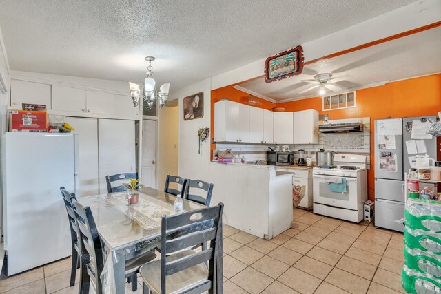 kitchen with hanging light fixtures, decorative backsplash, white cabinets, ceiling fan with notable chandelier, and white appliances