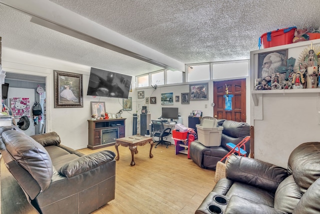 living room with hardwood / wood-style flooring, a fireplace, beam ceiling, and a textured ceiling