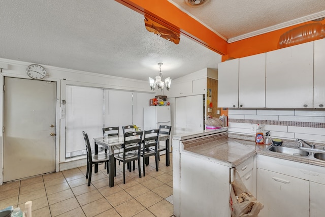 kitchen with white refrigerator, white cabinets, decorative light fixtures, ornamental molding, and a notable chandelier