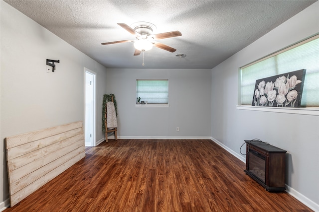 empty room with ceiling fan, dark wood-type flooring, and a textured ceiling