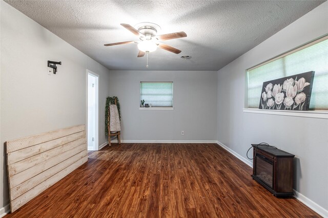 spare room featuring baseboards, wood finished floors, ceiling fan, and a textured ceiling
