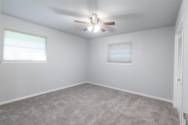 carpeted empty room featuring a textured ceiling, ceiling fan, and baseboards