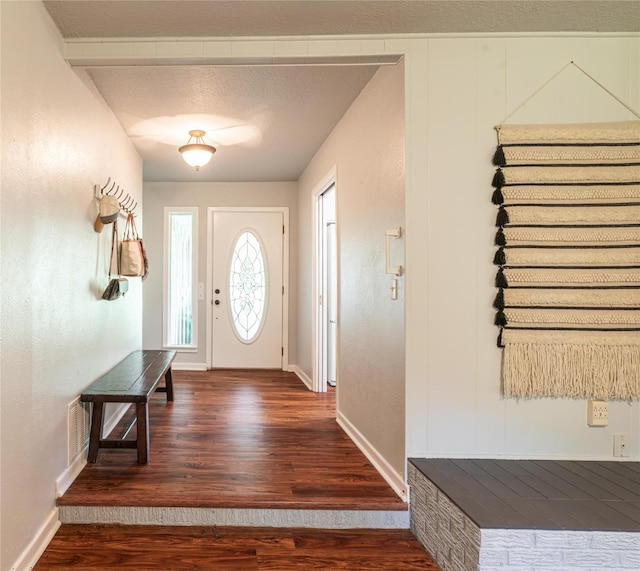 entryway featuring baseboards, visible vents, wood finished floors, and a textured ceiling