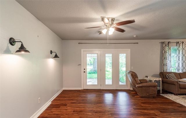 living area featuring dark wood finished floors, a textured ceiling, baseboards, and ceiling fan