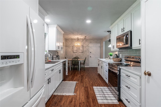 kitchen featuring a notable chandelier, light countertops, a sink, white cabinetry, and appliances with stainless steel finishes