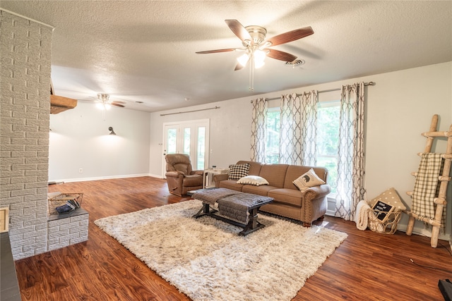 living room featuring ceiling fan, dark wood-type flooring, a textured ceiling, and a wealth of natural light