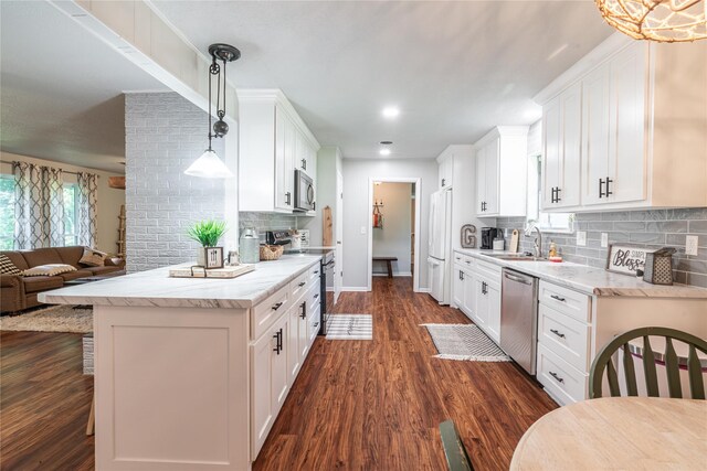 kitchen with open floor plan, dark wood-style flooring, stainless steel appliances, white cabinets, and light stone countertops