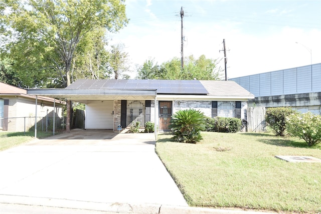 ranch-style home with a front lawn, solar panels, and a carport