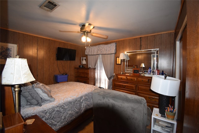 bedroom with crown molding, wood walls, and ceiling fan