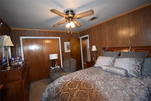 bedroom featuring a closet, wooden walls, carpet, crown molding, and ceiling fan