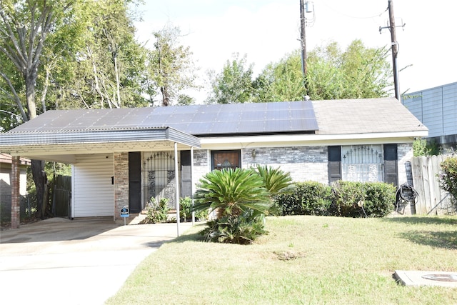 ranch-style home with a carport, solar panels, and a front yard