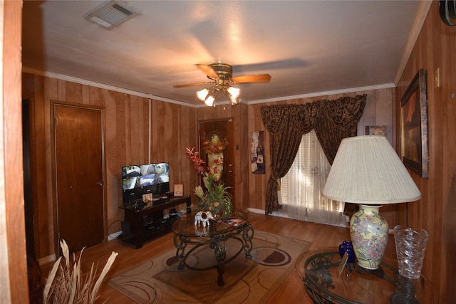 interior space with crown molding, wood walls, ceiling fan, and hardwood / wood-style flooring