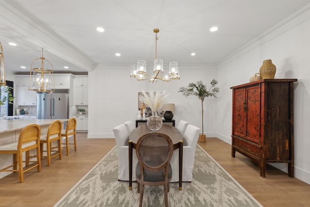 dining area with light wood-type flooring, crown molding, and a chandelier