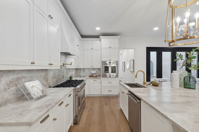 kitchen with sink, light hardwood / wood-style flooring, light stone countertops, stainless steel appliances, and white cabinets