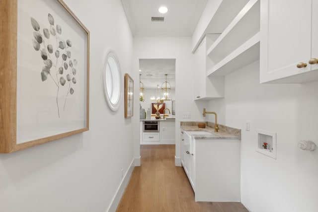 hallway featuring a notable chandelier, crown molding, light hardwood / wood-style flooring, and sink