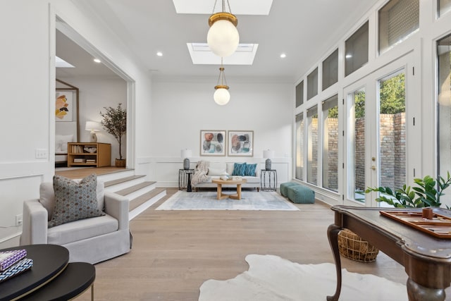 sitting room with a skylight, crown molding, and light hardwood / wood-style flooring