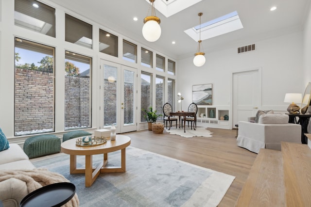 living room with light wood-type flooring, a skylight, and ornamental molding