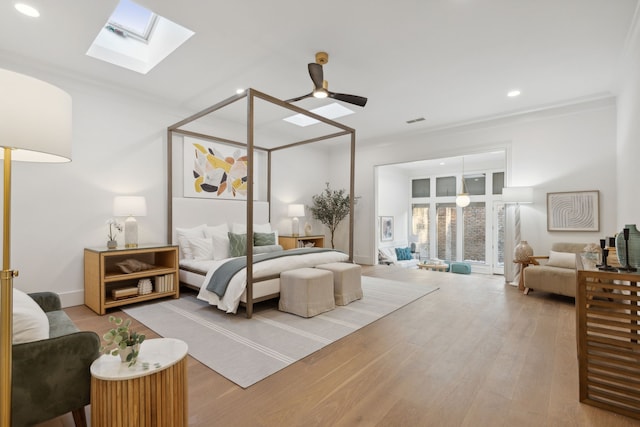 bedroom with ceiling fan, a skylight, ornamental molding, and light hardwood / wood-style floors