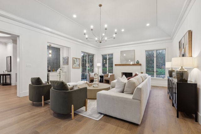 living room featuring ornamental molding, an inviting chandelier, and light wood-type flooring