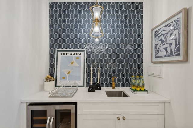 bar with white cabinetry, beverage cooler, hanging light fixtures, and sink