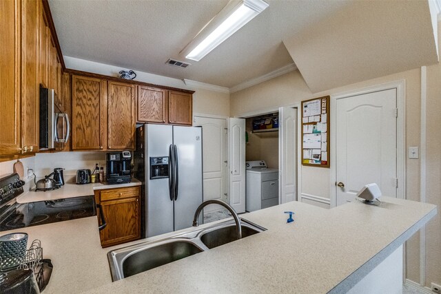 kitchen with a textured ceiling, sink, appliances with stainless steel finishes, ornamental molding, and washing machine and dryer