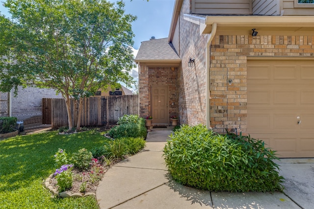 entrance to property with a garage and a lawn