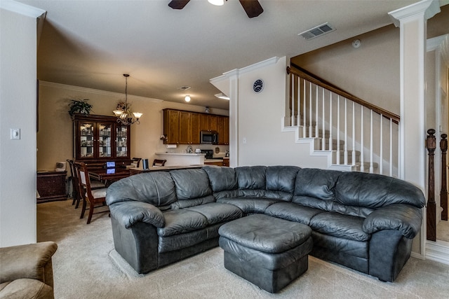 carpeted living room with ceiling fan with notable chandelier, crown molding, and ornate columns