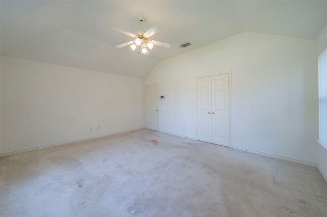 interior space with ceiling fan, light carpet, and vaulted ceiling