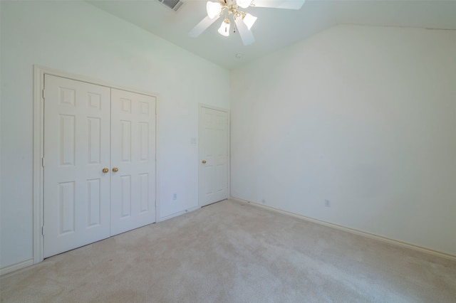 unfurnished bedroom featuring ceiling fan, light colored carpet, lofted ceiling, and a closet