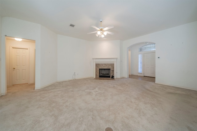 unfurnished living room with ceiling fan, a fireplace, and light carpet