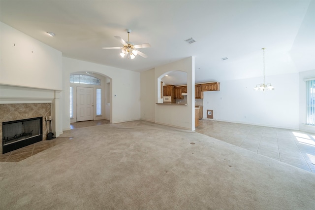 unfurnished living room with ceiling fan with notable chandelier, a tile fireplace, and light tile patterned flooring