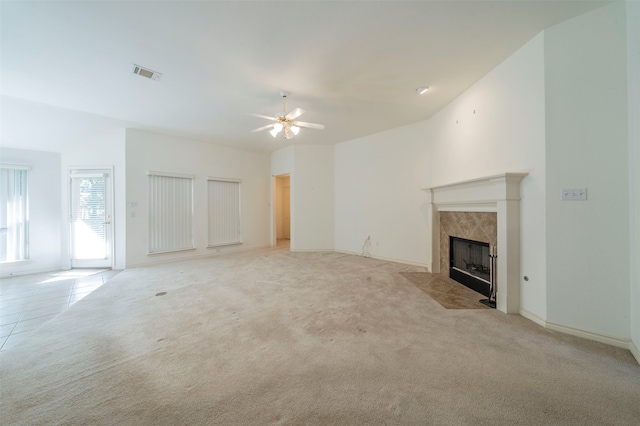 unfurnished living room with lofted ceiling, light colored carpet, ceiling fan, and a tile fireplace